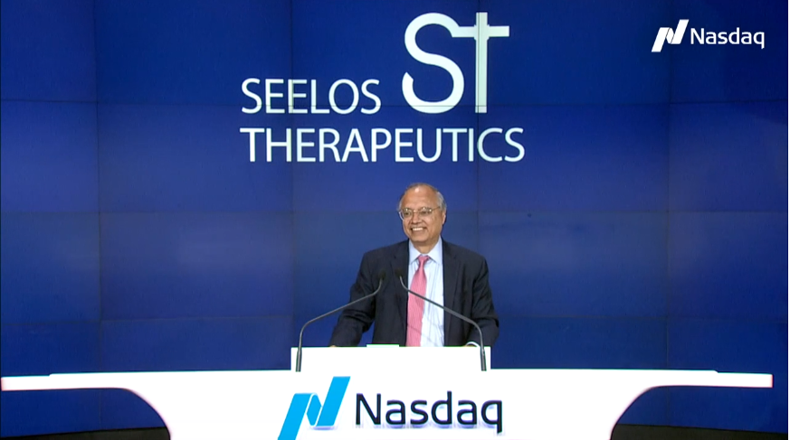 A man standing at a podium in front of a nasdaq sign.